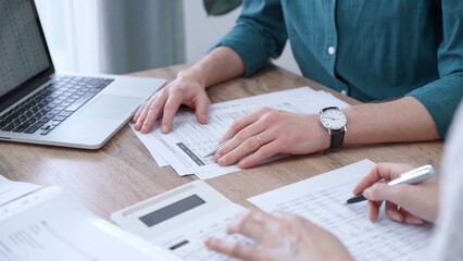 Auditor man wearing green shirt is reviewing papers and using a laptop with the colleague. Business people professionals analyzing financial documents. Finance, audit, and taxes
