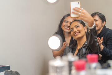 Happy customer taking selfie with make up artists in beauty salon