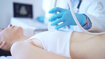 Naklejka premium Doctor man, wearing blue medical gloves, is using ultrasound machine to examine internal organs of a patient woman, close up vie. Female mammary gland health. Medicine