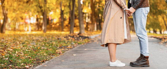 Lovers holding hands in golden forest, cropped, copy space