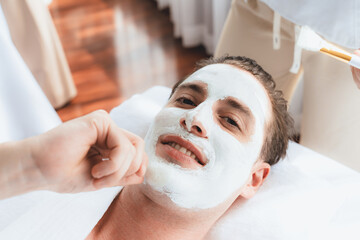 Serene ambiance of spa salon, man customer indulges in rejuvenating with luxurious face cream massage with modern daylight. Facial skin treatment and beauty care concept. Quiescent