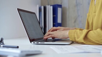 Woman with yellow blues working from home office typing on laptop computer keyboard. Business concept
