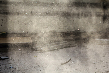 Sunlight filters through a cracked window, illuminating floating dust in a neglected room. The sparse, dusty scene evokes a sense of abandonment and forgotten memories.