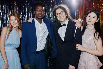 Group of diverse friends standing together at prom, smiling happily for camera