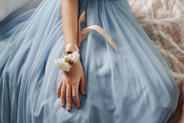 Elegant light blue dress with delicate flower corsage on wrist capturing soft and graceful style