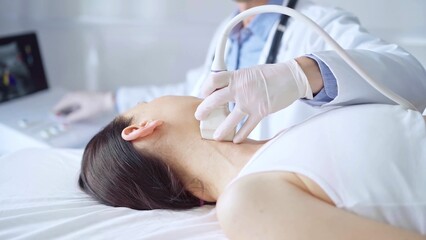 Obraz premium Doctor man is using ultrasound equipment on neck of female patient lying down for a medical examination. Medicine and science
