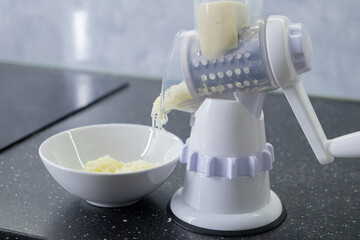 A modern hand grater that makes it easy to shred food. Grated cheese. Electric grater