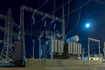 Detail of electrical substation including cables, transformers, insulation and circuit breakers under industrial lighting.