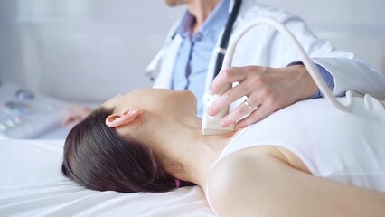 Obraz premium Doctor man is using ultrasound equipment on neck of female patient lying down for a medical examination. Medicine and science