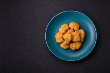 Delicious fresh crispy chicken nuggets on a dark concrete background
