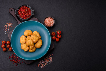 Delicious fresh crispy chicken nuggets on a dark concrete background