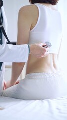 Fototapeta premium Doctor and patient. Physician is using stethoscope examining woman lungs from the back side. Medicine and health care