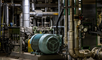 A large motor and pump connected to a maze of large diameter industrial piping