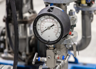 A pressure gauge with psi and kpa scales connected to industrial piping