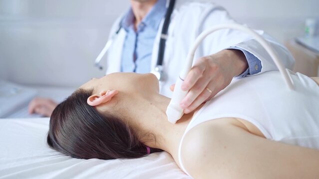 Doctor man is using ultrasound equipment on neck of female patient lying down for a medical examination. Medicine and science