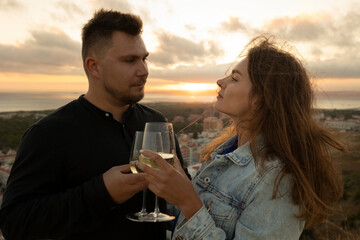 Loving couple drinking wine and enjoying scenic sunset view over city