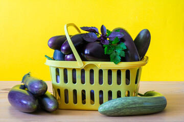 Fresh ripe eggplants in a yellow grocery container on a wooden table