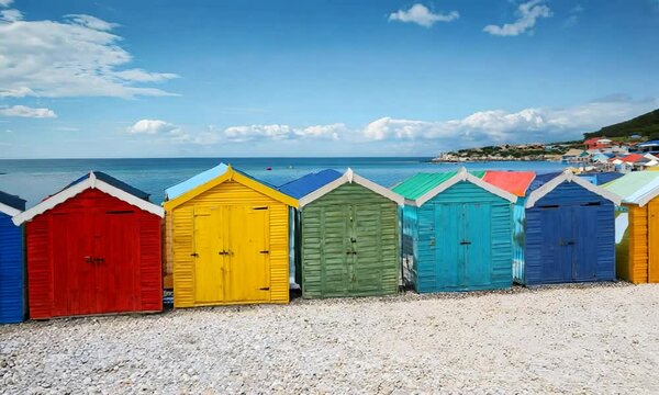 a row of colorful beach huts sitting on top of a sandy beach