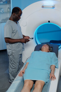 Medical professional operating MRI machine with patient inside scanner examining control panel for accurate imaging