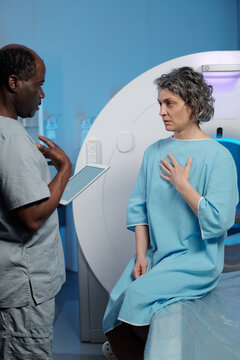 Senior woman wearing medical gown listening attentively to doctor explaining her diagnosis