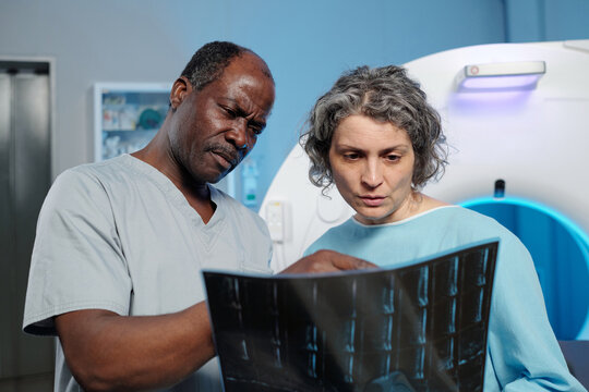 Medical professionals discussing scan results in hospital room filled with medical equipment