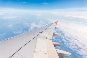 Fototapeta premium View from the airplane window at a beautiful cloudy sky and the airplane wing