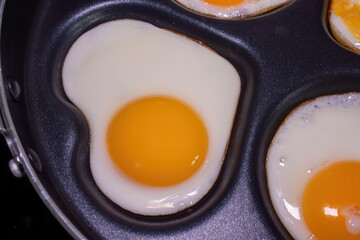 Close-up of fried eggs in a pan, with one egg shaped like a heart, highlighting the health and nutritional properties of eggs.