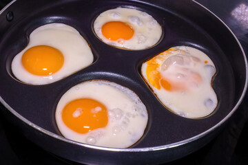Close-up of fried eggs in a pan, with one egg shaped like a heart, highlighting the health and...