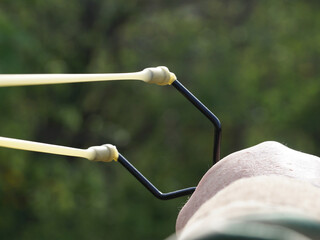 a stretched slingshot in a man's hand close-up against a forest background