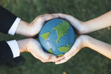 Top view businessman hand giving Earth globe to little boy as Earth day concept as corporate social responsible to contribute greener environmental protection for sustainable future generation. Gyre