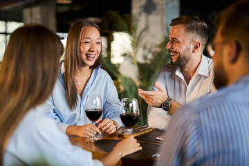 Happy entrepreneurs enjoying at a restaurant  while drinking wine with other two coworkers 