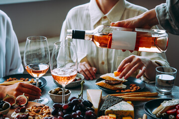 Pouring rose wine with classic snacks of cheese, bread and olives. Party or anniversary celebration.