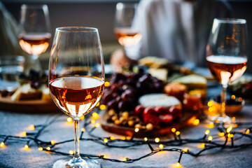 Wooden board with different kinds of cheese and glass of rose wine. Dinner or aperitivo party concept.