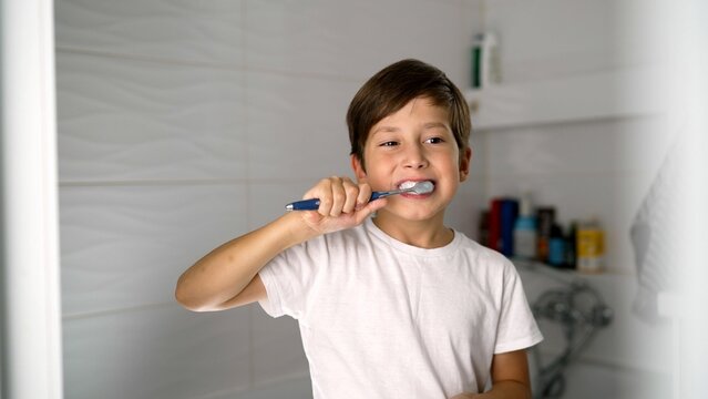 Young boy engaging in tooth brushing routine in a stylish modern bathroom.