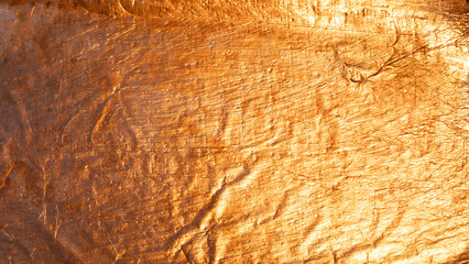 Abstract background created by crumpled shiny golden metallic texture