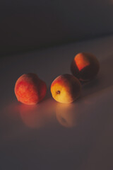 three peaches on a peach background with a beautiful shadow. juicy ripe peaches in sunlight and shadow. 