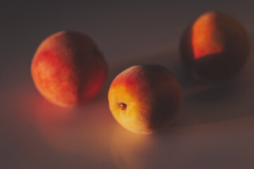 three peaches on a peach background with a beautiful shadow. juicy ripe peaches in sunlight and shadow. 