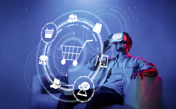 Happy man using VR headset and shopping online while sitting at sofa with shopping bags. Smart person looking at online market hologram and icon with neon background. Innovation technology. Deviation.
