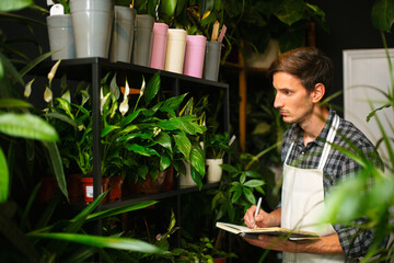 A male worker checking out flowers in a flower shop and writing them down