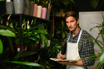 A male worker checking out flowers in a flower shop and writing them down