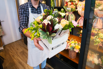A male worker in a flower shop holding a big flower bouquet