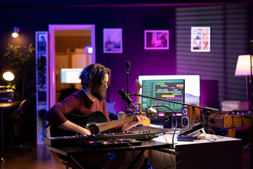 Songwriter artist producing sounds with acoustic guitar and equalizer in his home studio, using a...