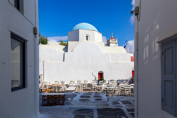 Mykonos island, Greece. Famous old town narrow street view with outside restaurant and church