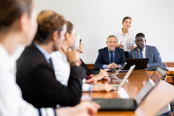 Two professional mature male board executives with the help of a young female executive assistant...