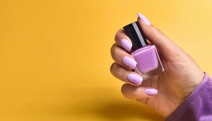A hand with soft lilac nails holding a square bottle of matching purple polish against a smooth yellow background. The pastel hues create a visually pleasing contrast, emphasizing the nail color.