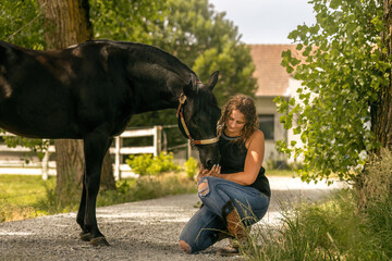 Equestrian lifestyle: A woman and her quarter horse stallion interacting together in summer outdoors