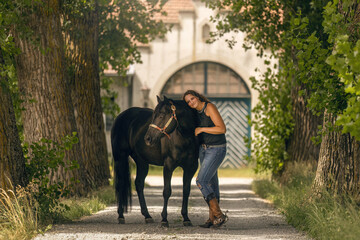 Equestrian lifestyle: A woman and her quarter horse stallion interacting together in summer outdoors