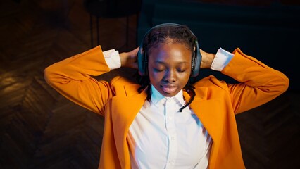 Young pupil relaxing with modern music on headphones, sitting laid back and taking a break from...