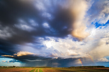 Storm clouds in the sky, rain on the horizon, summer season. Two rainbows
