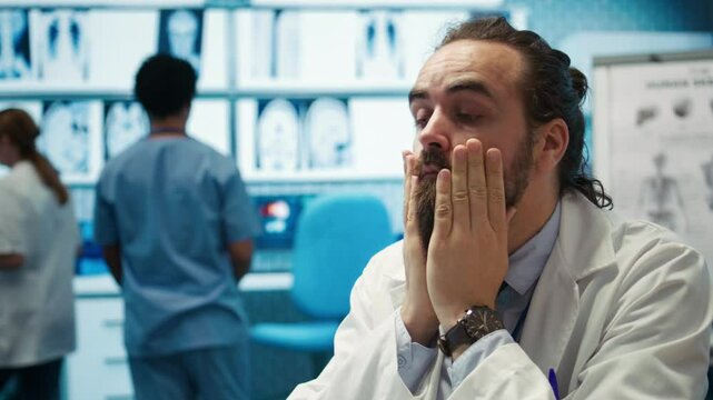 Overworked stressed physician struggling to find a diagnostic cabinet, consulting hospital records and radiography results. Frustrated medic working under pressure at treatment center. Camera B.